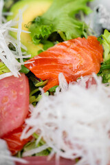 Fresh salad with vibrant ingredients including sliced salmon, avocado, leafy greens, and shredded vegetables. The close-up shot highlights the freshness and texture of the components