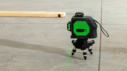 Laser level projecting green beam on concrete floor during home renovation