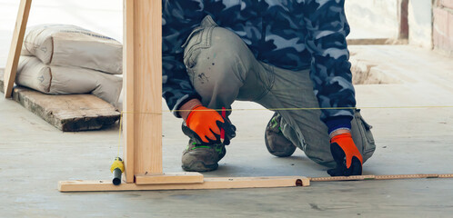 Construction worker measuring and marking guidelines on concrete floor