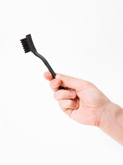 A hand grips a sleek black toothbrush on a bright white background