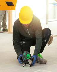 Construction worker using rotating laser level on tripod at construction site