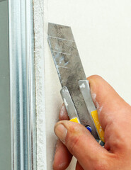 Construction worker cutting drywall with utility knife during home renovation
