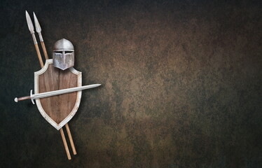 knight's helmet sword wooden shield and two spears on grunge background