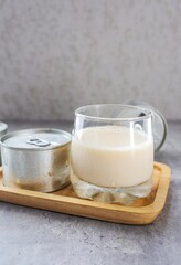 Glass of  fresh milk with canned milk, tinned milk on grey background	