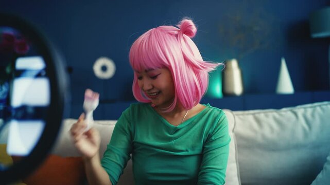 Korean pink-haired woman blogger recording makeup tutorial on phone, beauty vlog