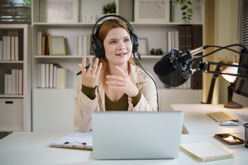 Female hosting a podcast episode, gesturing expressively while speaking into a microphone with...