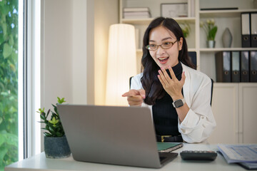Excited female entrepreneur reacting with enthusiasm to good news while working on her laptop.