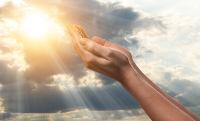 Woman praying against beautiful sky with sun, closeup