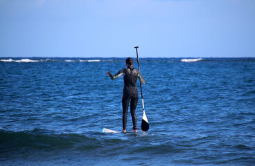 Young woman in wetsuit stand up paddling at the sea (Atlantic ocean, Tenerife, Spain)