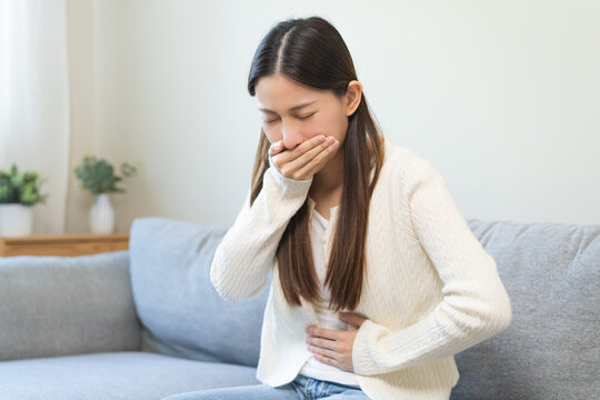 Fototapeta Unhappy pregnant asian young woman, pain girl suffering from nausea, having vomit feeling sick covering mouth, touching belly having problem throwing up from food poisoning, lady with morning sickness