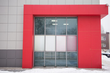 Modern building entrance featuring large glass doors framed by a vibrant red structure, showcasing contemporary architectural design and urban aesthetics