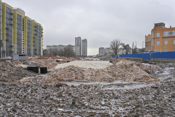 Construction of an asphalt road in winter among high-rise buildings