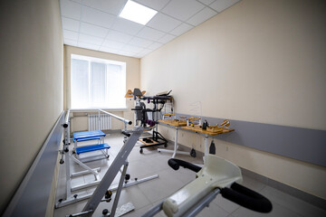 A rehabilitation room features diverse exercise and physical therapy equipment, including a gait training machine, a treadmill, a stationary bicycle, manipulative tools, designed for patient recovery.