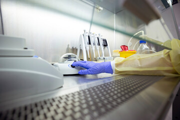 Equipment for DNA/RNA extraction, including pipettes and a shaker, is inside a ventilated safety cabinet in a laboratory