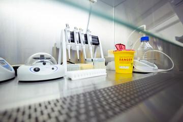 Equipment for DNA/RNA extraction, including pipettes and a shaker, is inside a ventilated safety cabinet in a laboratory