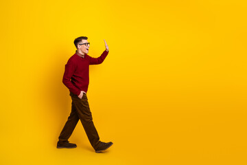 Young Man Gesturing and Smiling Against Bright Yellow Background in Stylish Outfit