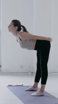 Healthy wellness caucasian woman with long hair in sportswear doing warm-up before main exercise or yoga. Arching and stretching the muscles of the back and neck. Female Fitness sport. Limbering-Up