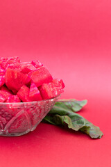 Diced beets in a glass bowl on a reddish-pink background