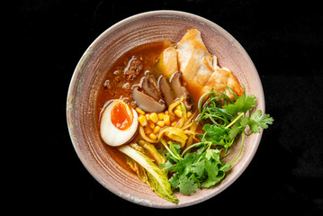A bowl of ramen with rich broth, garnished with a soft-boiled egg, mushrooms, corn, fresh greens, and grilled chicken. The vibrant colors and varied textures create a visually appealing presentation
