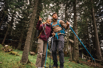 Obraz premium Curious Hiking Couple Observing the Distant View in Mountain Forest
