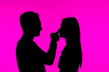 Silhouette of couple interacting against vibrant pink backdrop