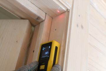 Laser distance measurer with clear digital display is used to measure the height of a wooden...