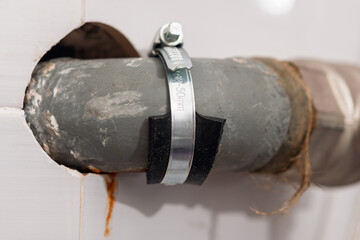 Pipe repair clamp tightly secures rubber patch on old pipe, demonstrating emergency plumbing fix...