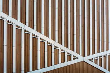 Modern building facade with geometric metal and wood panels forms dynamic pattern, emphasizing urban architecture and contemporary design.