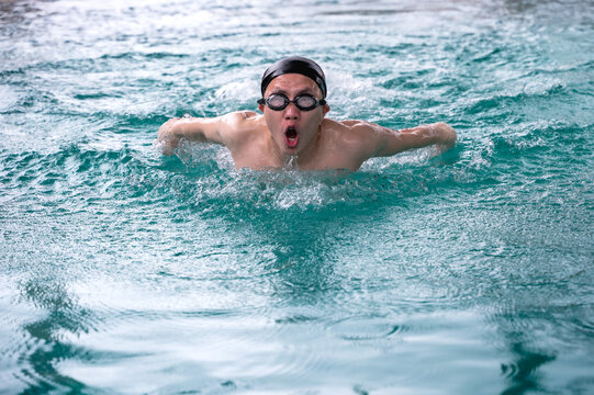 Asian male swimmer swimming butterfly stroke in pool