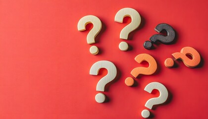 Wooden question marks arranged on a red surface.