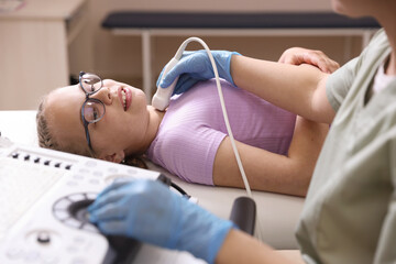 Sonographer conducting girl's thyroid gland ultrasound examination in clinic, closeup