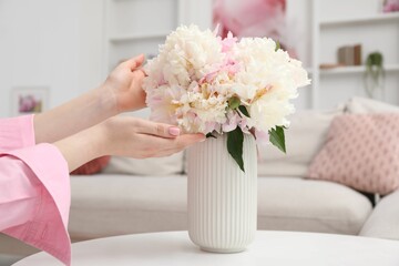 Woman with bouquet of beautiful peonies at home, closeup