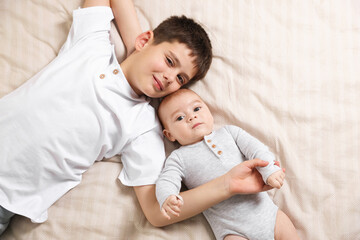 Cute little brothers on bed, top view
