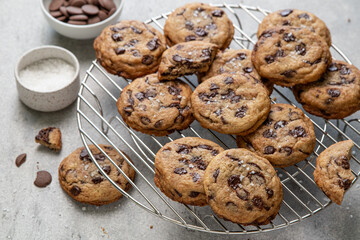 Homemade American brown butter chewy, fluffy and soft chocolate chip cookies on a cooling rack with salt. Biscuits for children. Selective focus.