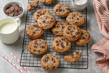 Homemade American brown butter chewy, fluffy and soft chocolate chip cookies on a cooling rack with salt and milk. Biscuits for children. Selective focus.