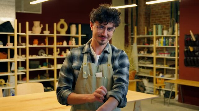 Man portrait Caucasian guy potter sculptor craftsman in pottery workshop looking at camera roll up sleeves small business owner designer master art studio ceramics shop male posing artisan craft hobby