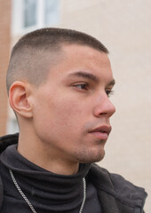 Young man outdoors on a cool day in an urban area surrounded by buildings.