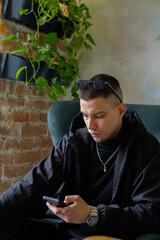Young man while looking at his smartphone in a cozy indoor setting during the day