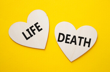 Life or Death symbol. Concept word Life or Death on wooden hearts. Beautiful yellow background....