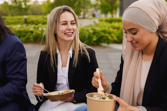 Diverse business women eating together healthy lunch outside of office building - Entrepreneur, colleagues and multiracial people concept