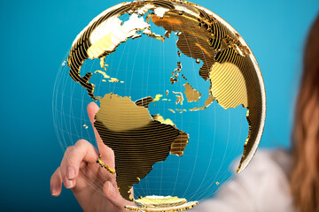 Woman interacts with a golden globe, symbolizing global reach and international business.