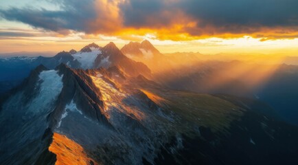 Mountains landscape with snowy peaks under golden sunset clouds