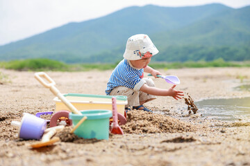  강가 모래사장에서 노는 귀여운 유아