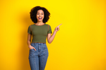 Cheerful young woman pointing with enthusiasm on a vibrant yellow background, showcasing energy and...