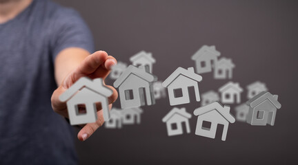 Image depicts a person choosing from multiple virtual house icons, representing real estate...