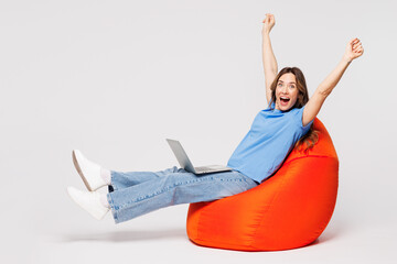 Full body young IT woman she wears blue t-shirt casual clothes sit in bag chair hold use work on...