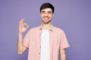 Young smiling happy cheerful man he wearing pink shirt t-shirt casual clothes showing okay ok...