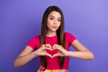 Young brunette woman making heart hand gesture wearing a pink outfit on vivid background,...