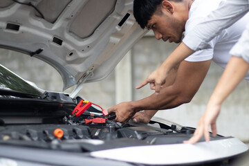 Professional male technician checks broken car engine using tools to diagnose power problems and...
