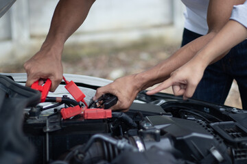 Professional male technician checks broken car engine using tools to diagnose power problems and...